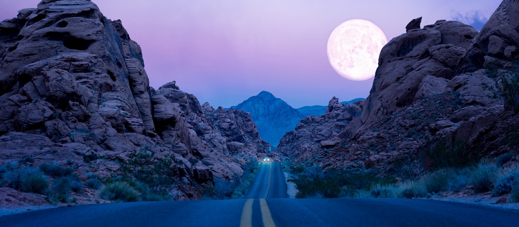 La luna cuelga baja sobre una carretera en el desierto del suroeste