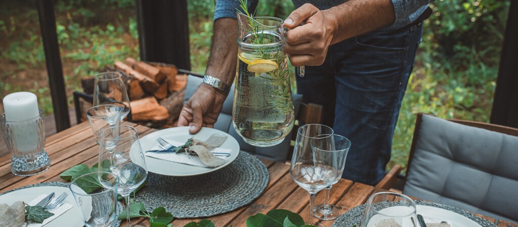 A man sets an outdoor dining table in anticipation of his guests