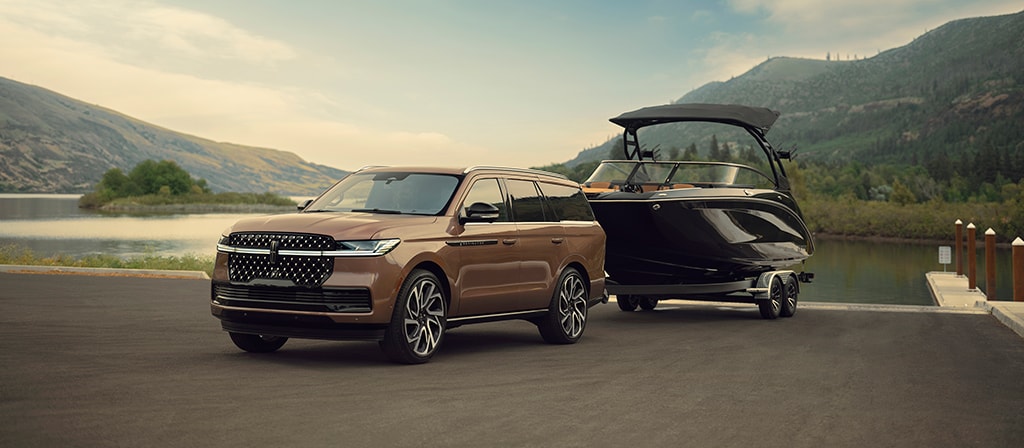 A 2026 Lincoln Black Label Navigator® has a boat hitched up by the water