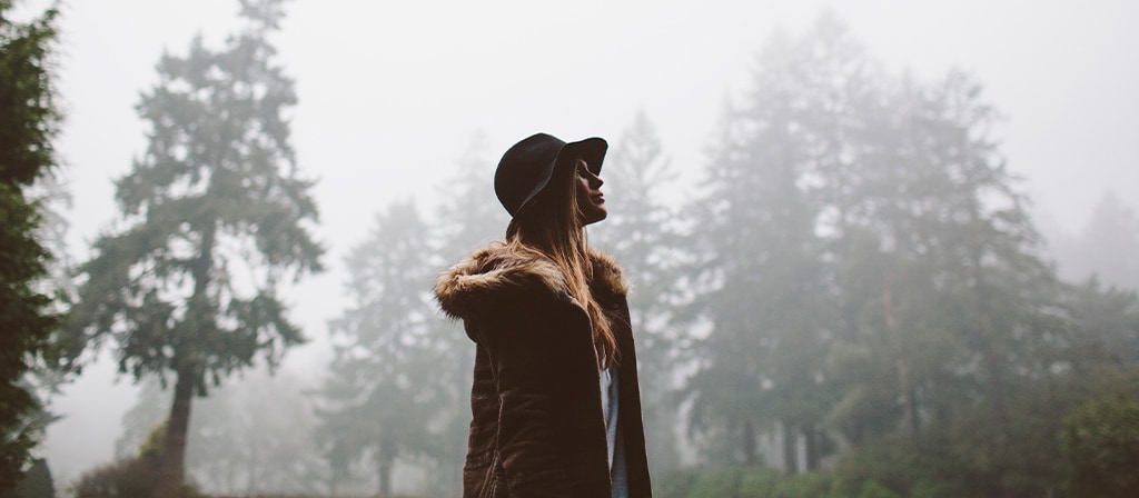 A woman walks through the forest following the conclusion of a rain storm