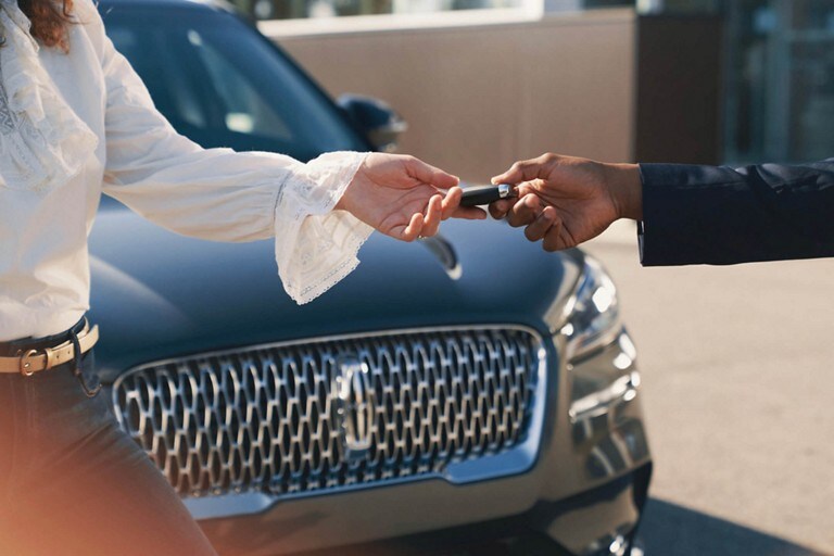 A Lincoln service representative is shown handing over the keys of a Lincoln vehicle to a customer