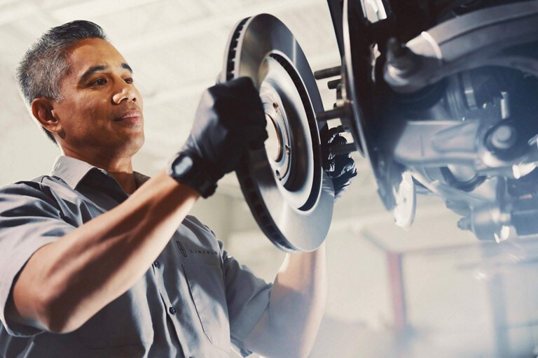 A Lincoln service technician is shown measuring the tire pressure of a Lincoln vehicle as part of a 200 point inspection