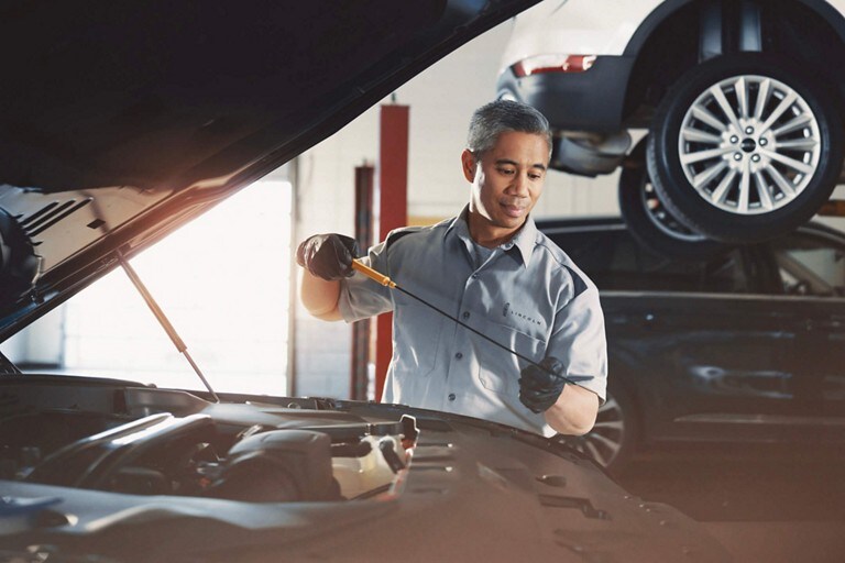 A Lincoln service technician is shown inspecting the engine of a Lincoln vehicle as part of the 200 point inspection