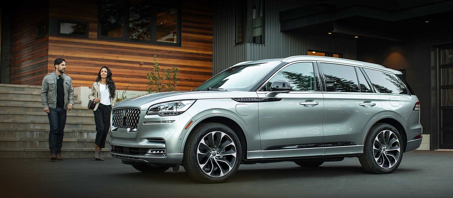 A man and woman walking away from a modern home toward a 2022 Lincoln Aviator® Grand Touring SUV
