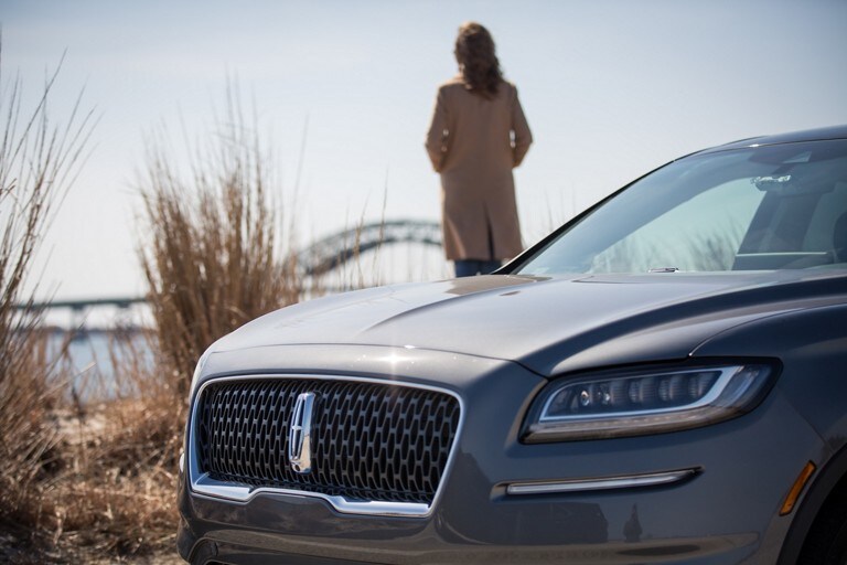 A woman standing near a body of water next to a 2021 Lincoln Nautilus® Black Label SUV