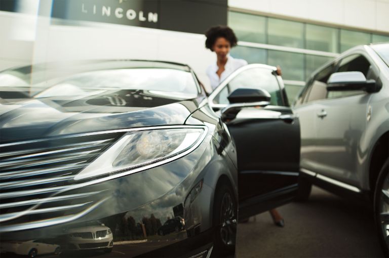 Imagen de un cliente abriendo la puerta de un vehículo Lincoln en un concesionario
