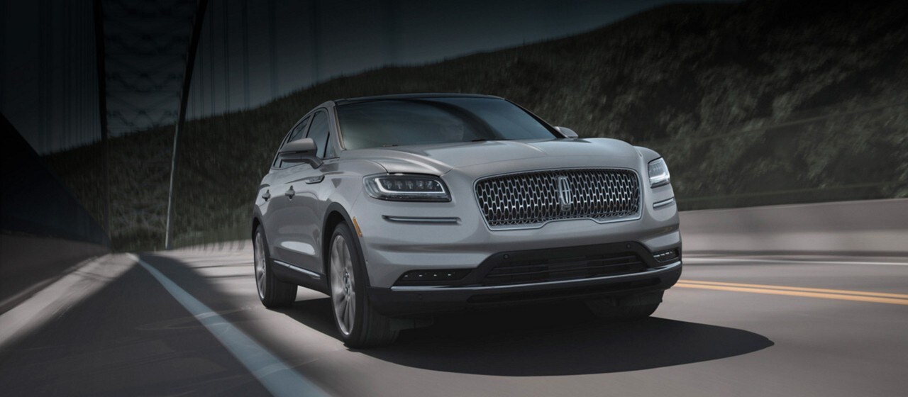 Se muestra un Lincoln M K T 2018 con exterior en platino blanco pasando por un puente
