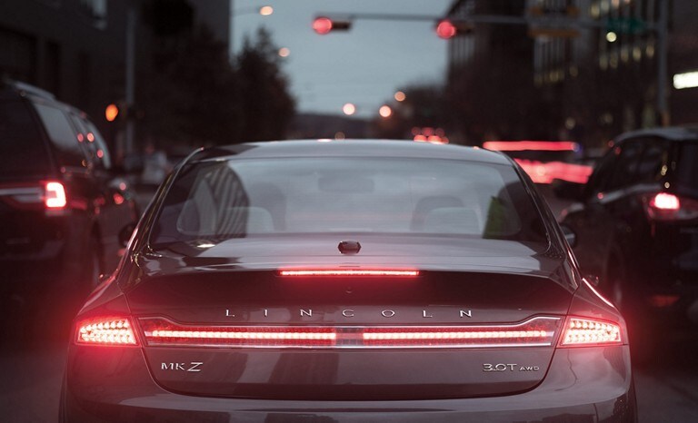 Un Lincoln MKZ negro en un embotellamiento de tráfico donde la característica de control de velocidad adaptativo con cámara para visión trasera y capacidad de frenado y avance se destaca