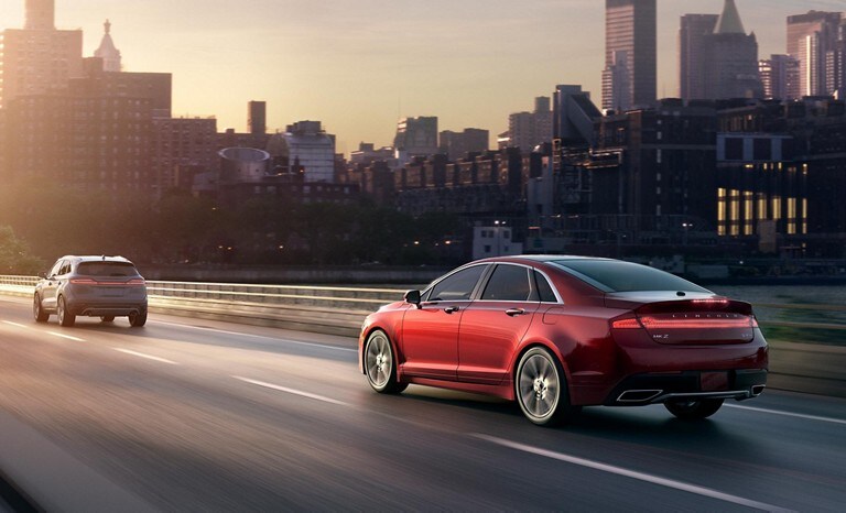 Un Lincoln MKZ rojo en una autopista urbana mantiene una distancia segura usando la característica de indicación de alerta de distancia