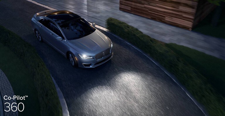 Un sedán Lincoln gris en una carretera por la noche para demostrar el funcionamiento de los faros delanteros con luces altas automáticas, los cuales forman parte de Co-Pilot360