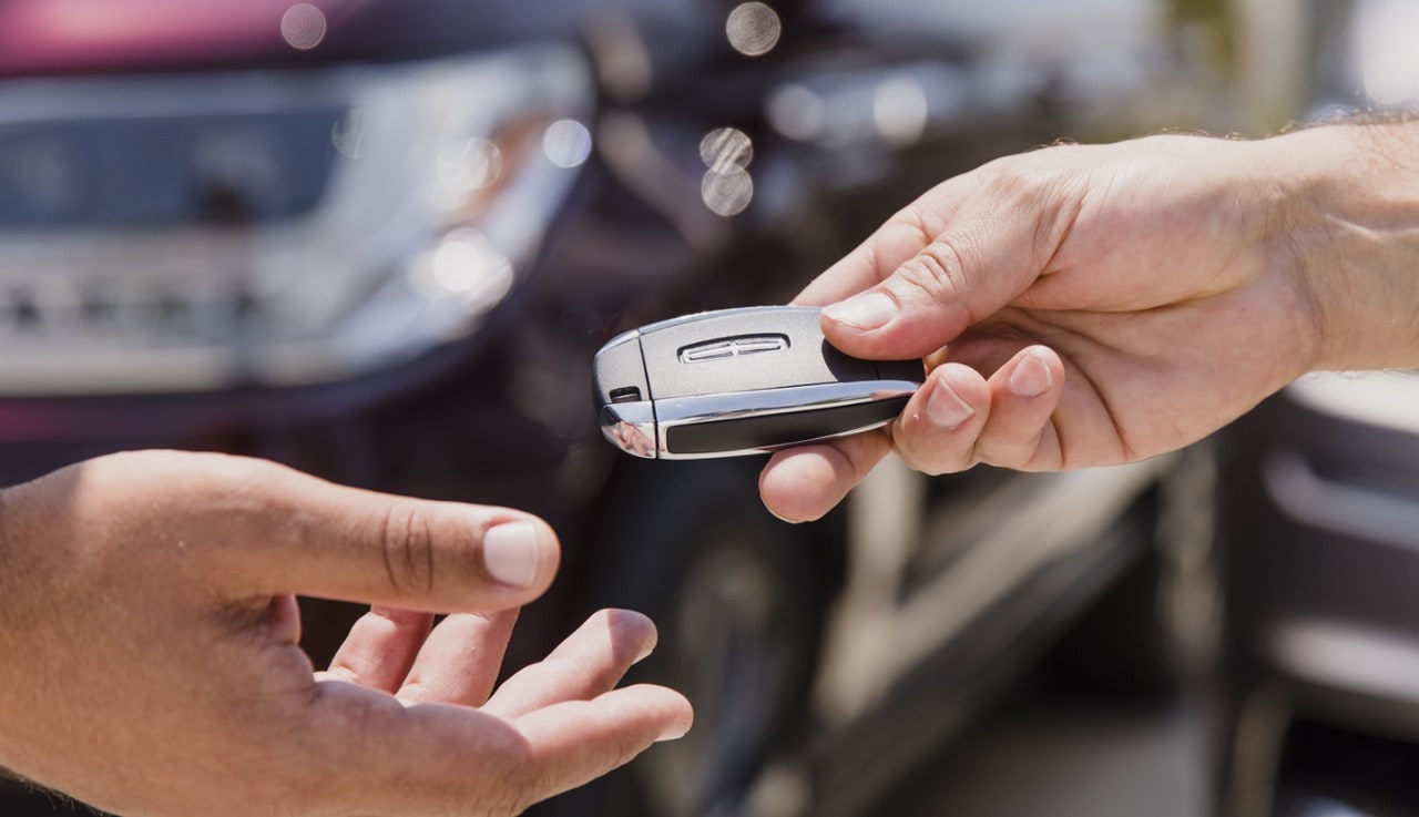 Close up shot of hands in a handoff of a Lincoln key fob