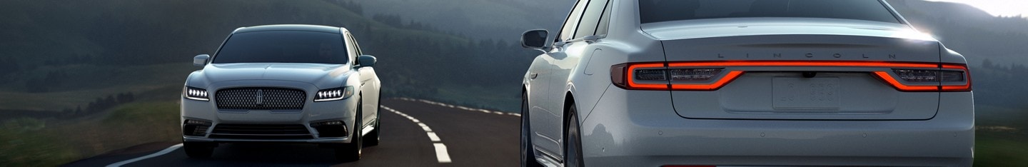 A pair of white Lincoln MKZs passing each other on a one lane road