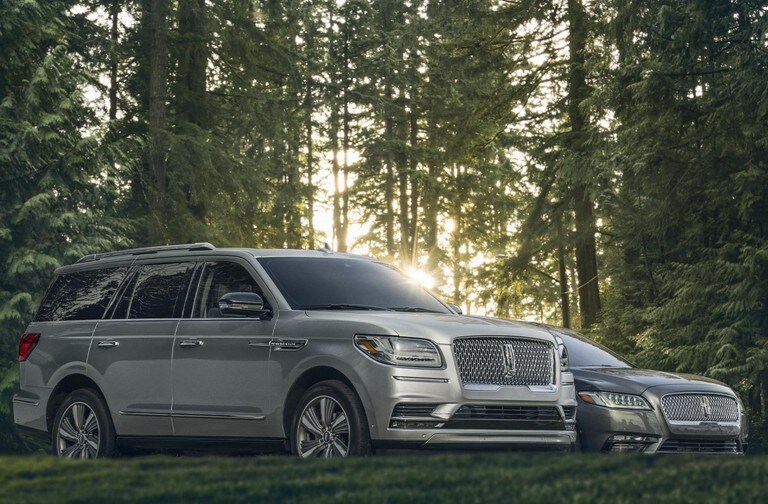 Silver Lincoln Navigator and Continental out in the forest