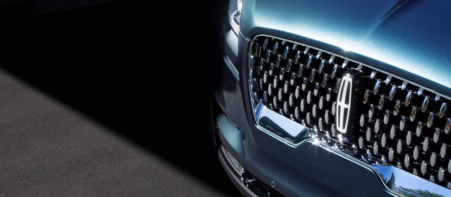 The grille of a Lincoln Black Label vehicles beams radiantly in the sunshine