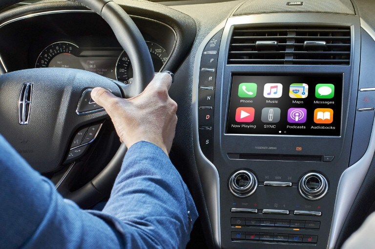 A driver uses his voice to control the Apple CarPlay interface on the console.