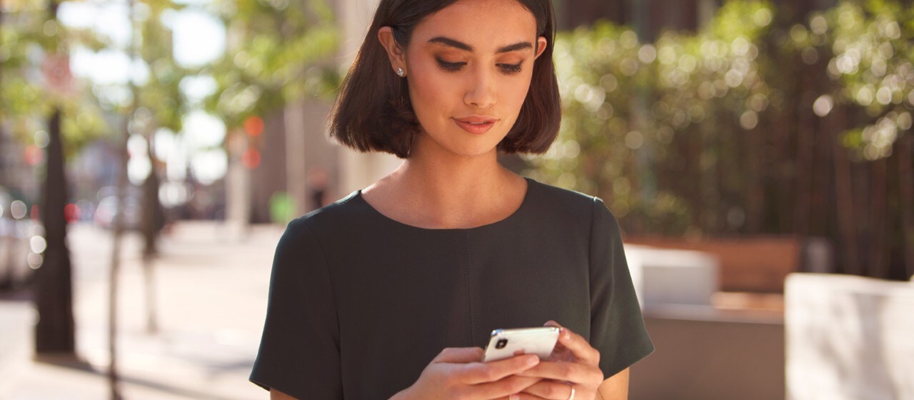 Woman holding phone outside building