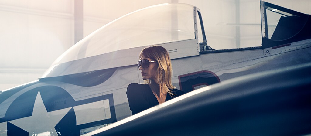 A woman is shown next to a vintage airplane to evoke the inspiration for the 2025 Lincoln Black Label Flight theme