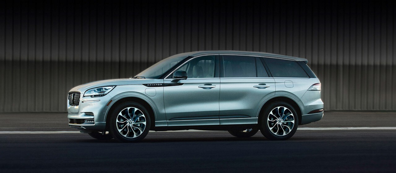 A 2023 Lincoln Aviator® Grand Touring model is shown parked next to an airplane hangar