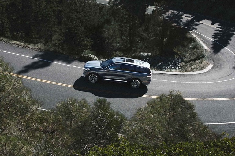Se muestra una Lincoln Aviator® Black Label Grand Touring 2023 andando por un camino serpenteante