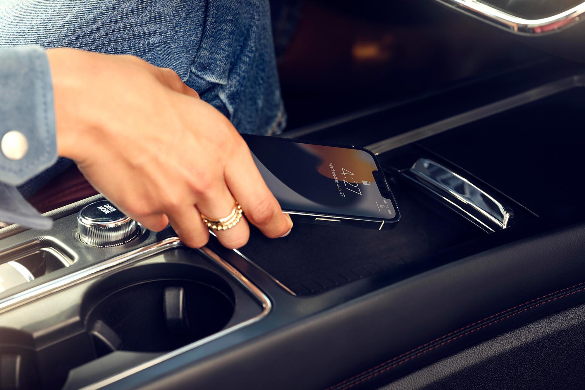 A woman's hand holding a smart phone over the Lincoln Corsair center console.
