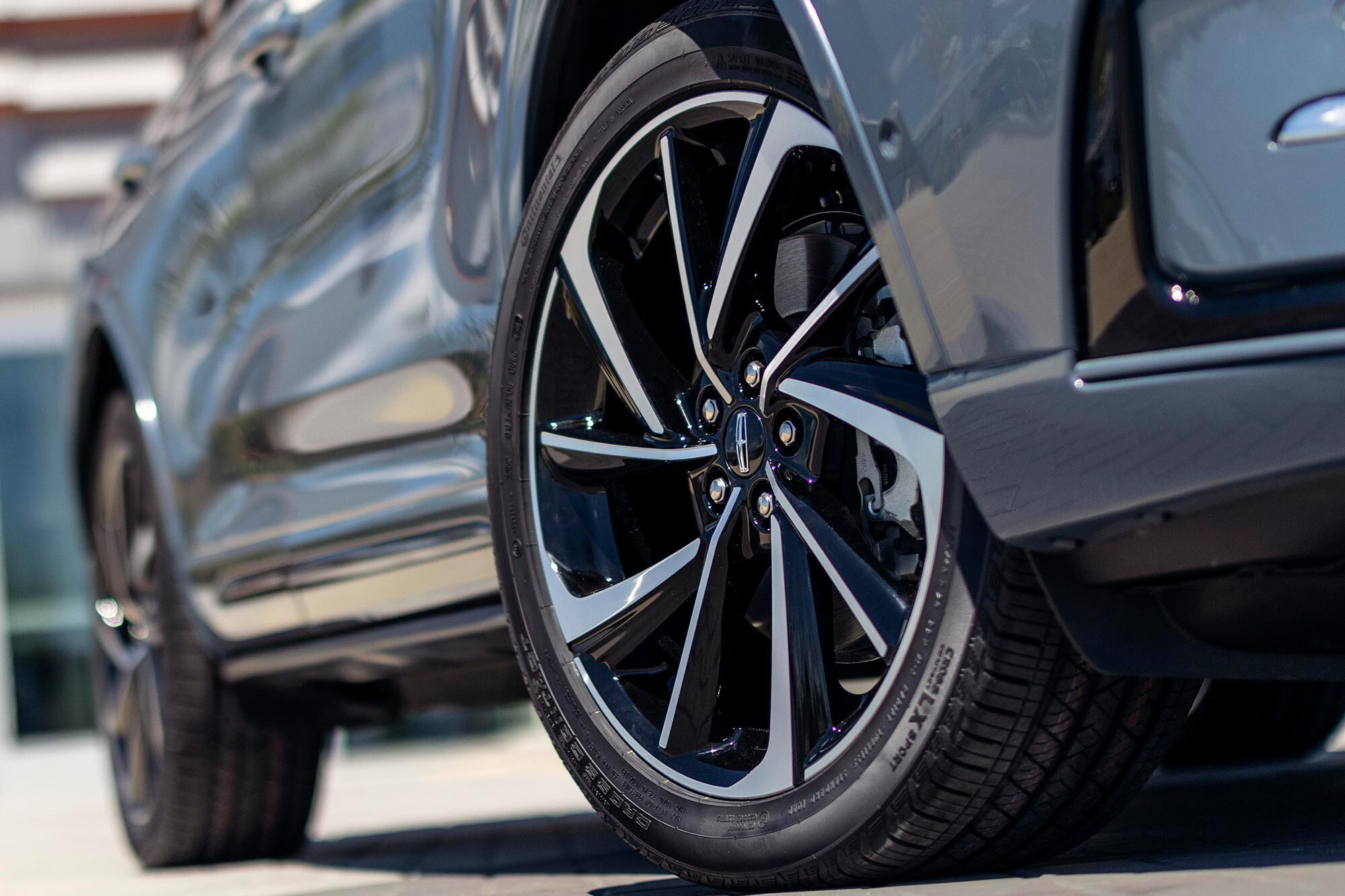 The front wheel of the Lincoln Corsair with a black and silver rim.