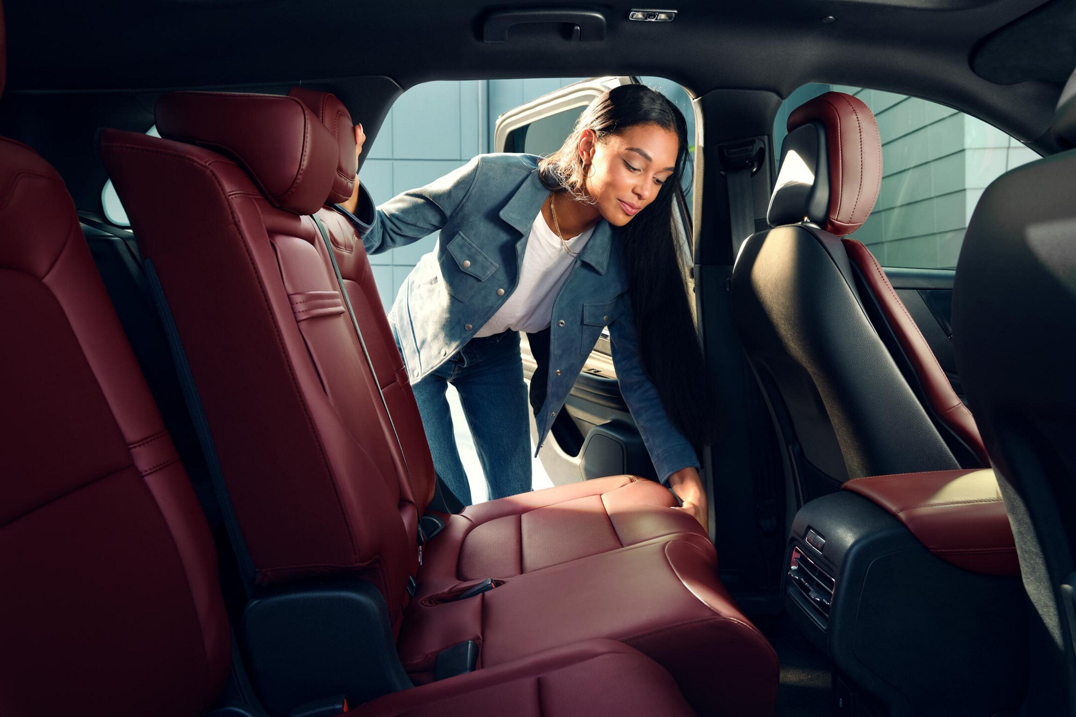 A woman adjusting red second-row sliding seats.