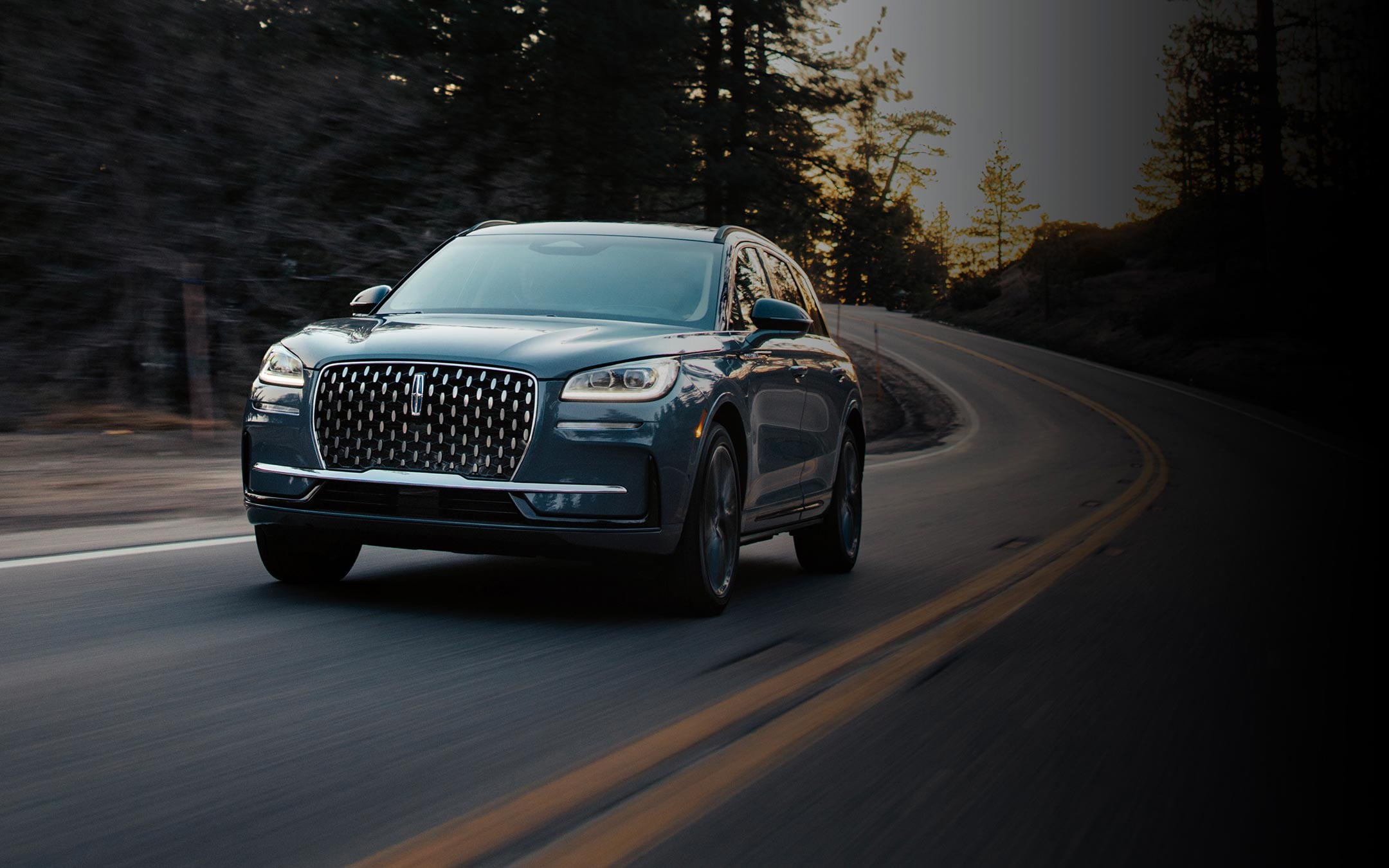 2025 Lincoln Corsair® Reserve model in the Whisper Blue exterior color is driven over a bridge at night