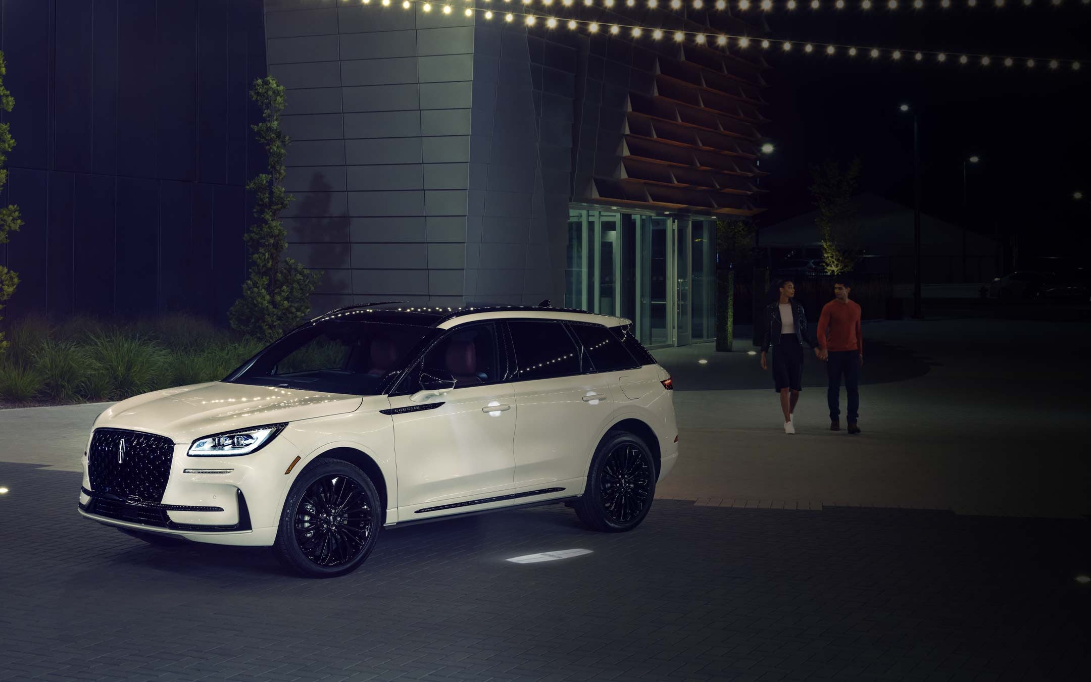 A couple approaches a 2026 Lincoln Corsair® SUV as the Lincoln Embrace illumination guides the way