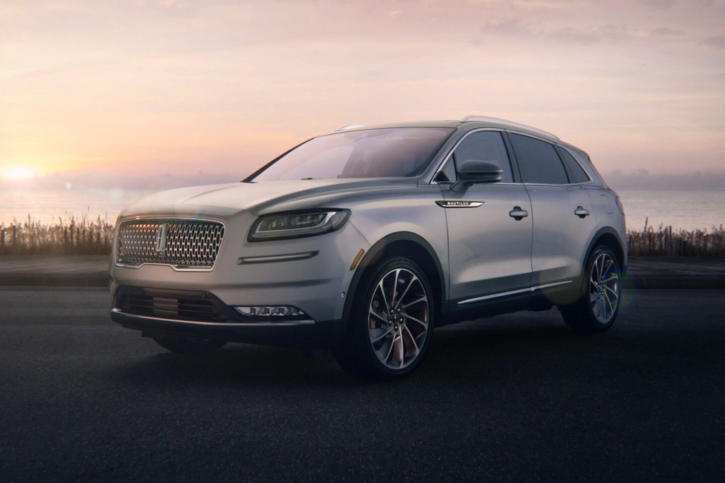 Una SUV Lincoln Nautilus® estacionada junto al océano al amanecer