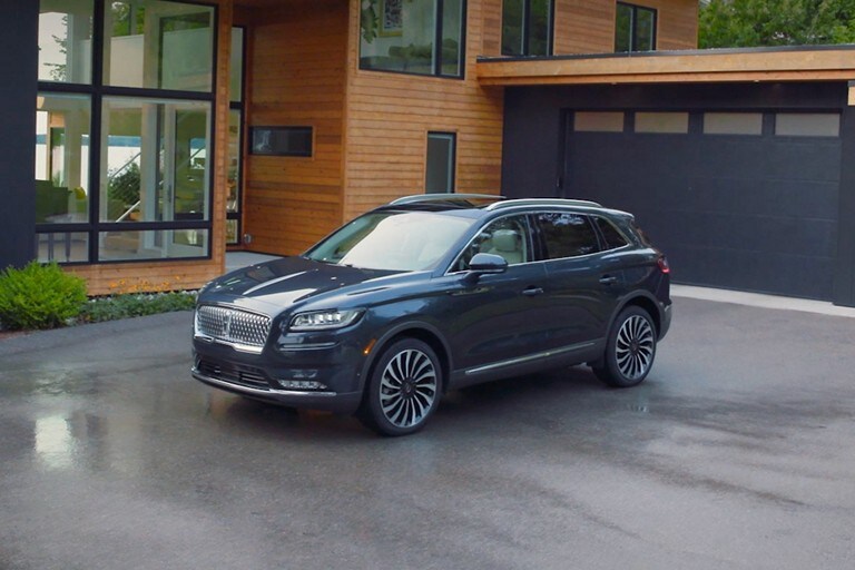 A Lincoln Nautilus® SUV is parked in the driveway of a modern home