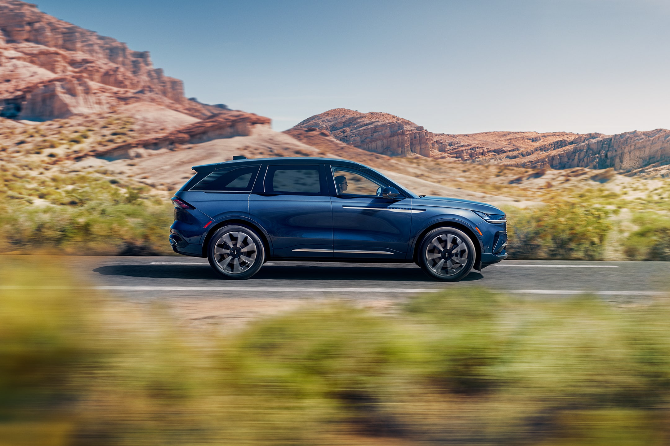 Una SUV Lincoln Nautilus® 2024 se desplaza por una carretera junto al mar.