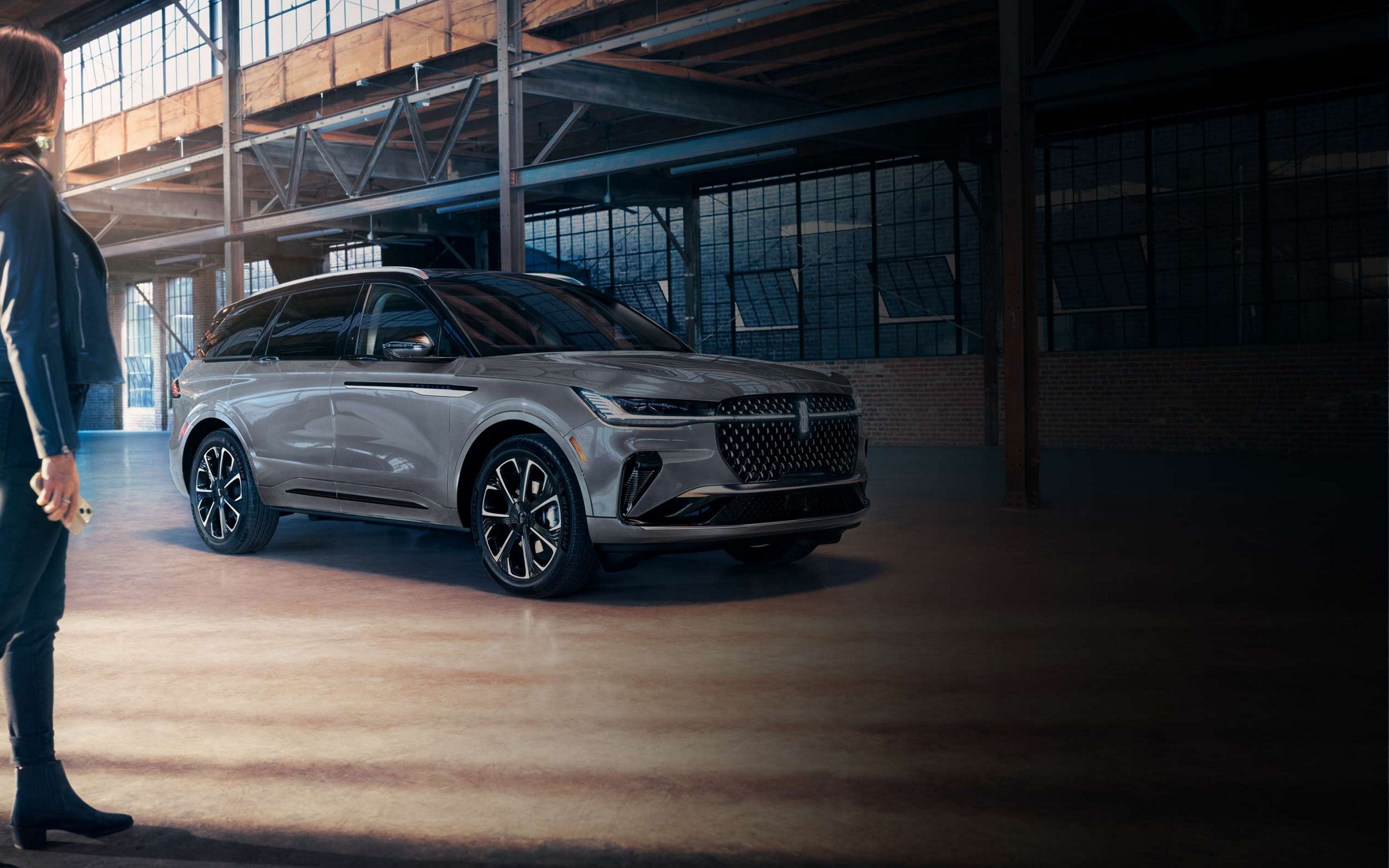 A woman is seen near a 2025 Lincoln Nautilus® SUV as the Lincoln Embrace lighting sequence takes place