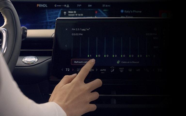 A person interacts with the center touch screen to adjust available Auto Air Refresh