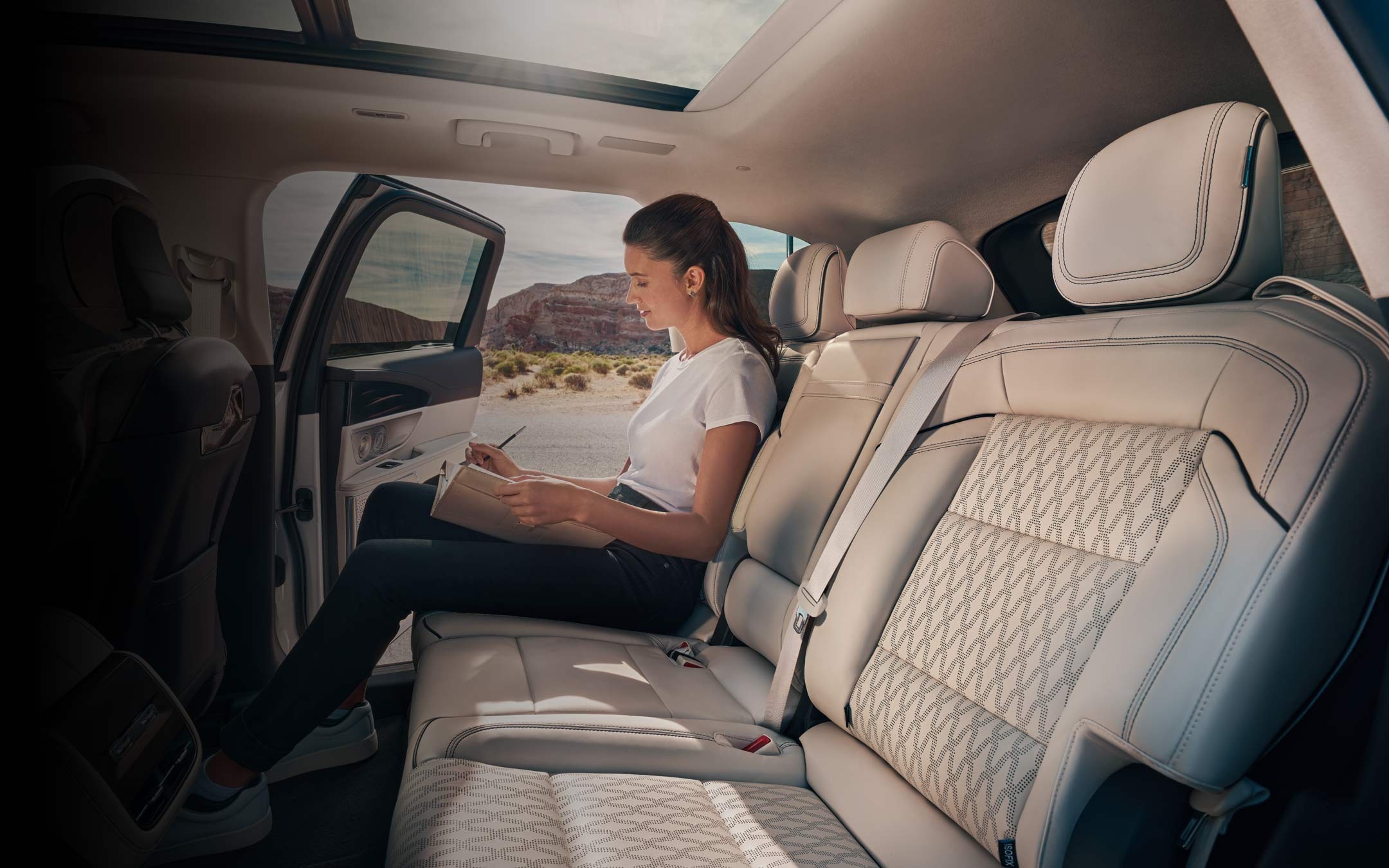 A woman is seated in the second row of a 2026 Lincoln Black Label™ Nautilus® SUV with the Chalet interior theme