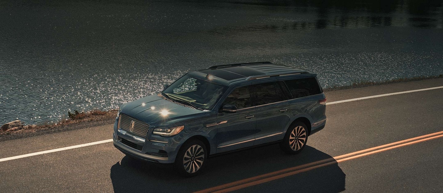 Una SUV Lincoln Navigator® 2023 andando junto a un lago impecable.