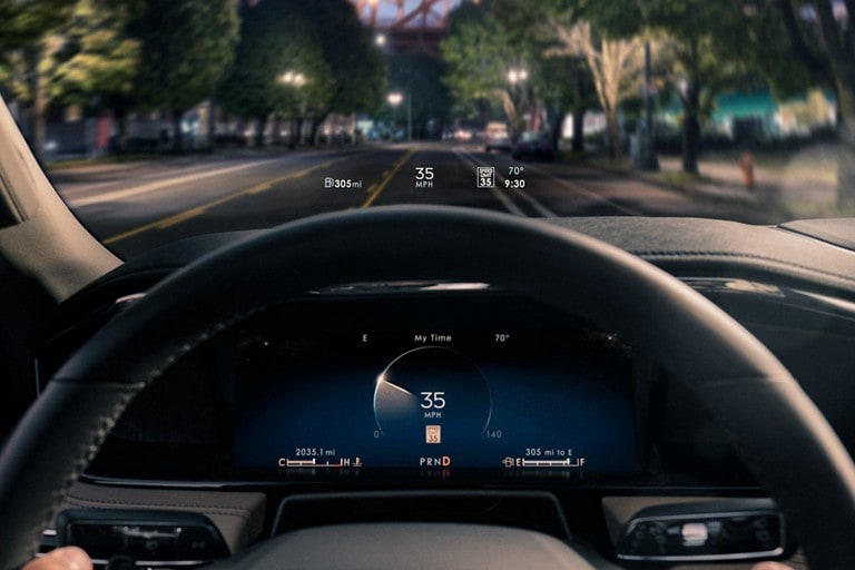Head-up display information is being projected above the steering wheel at night.