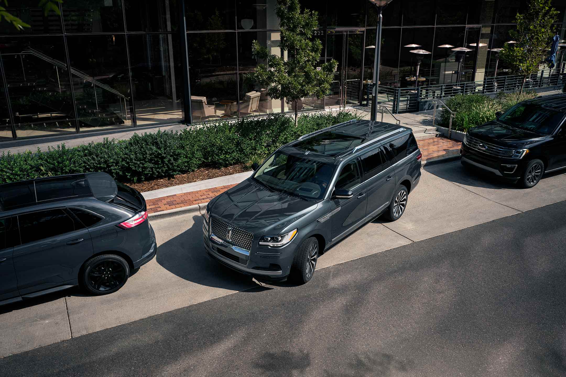 Una SUV Lincoln Navigator® 2024 estacionada en paralelo entre dos vehículos fuera de un hotel de lujo.