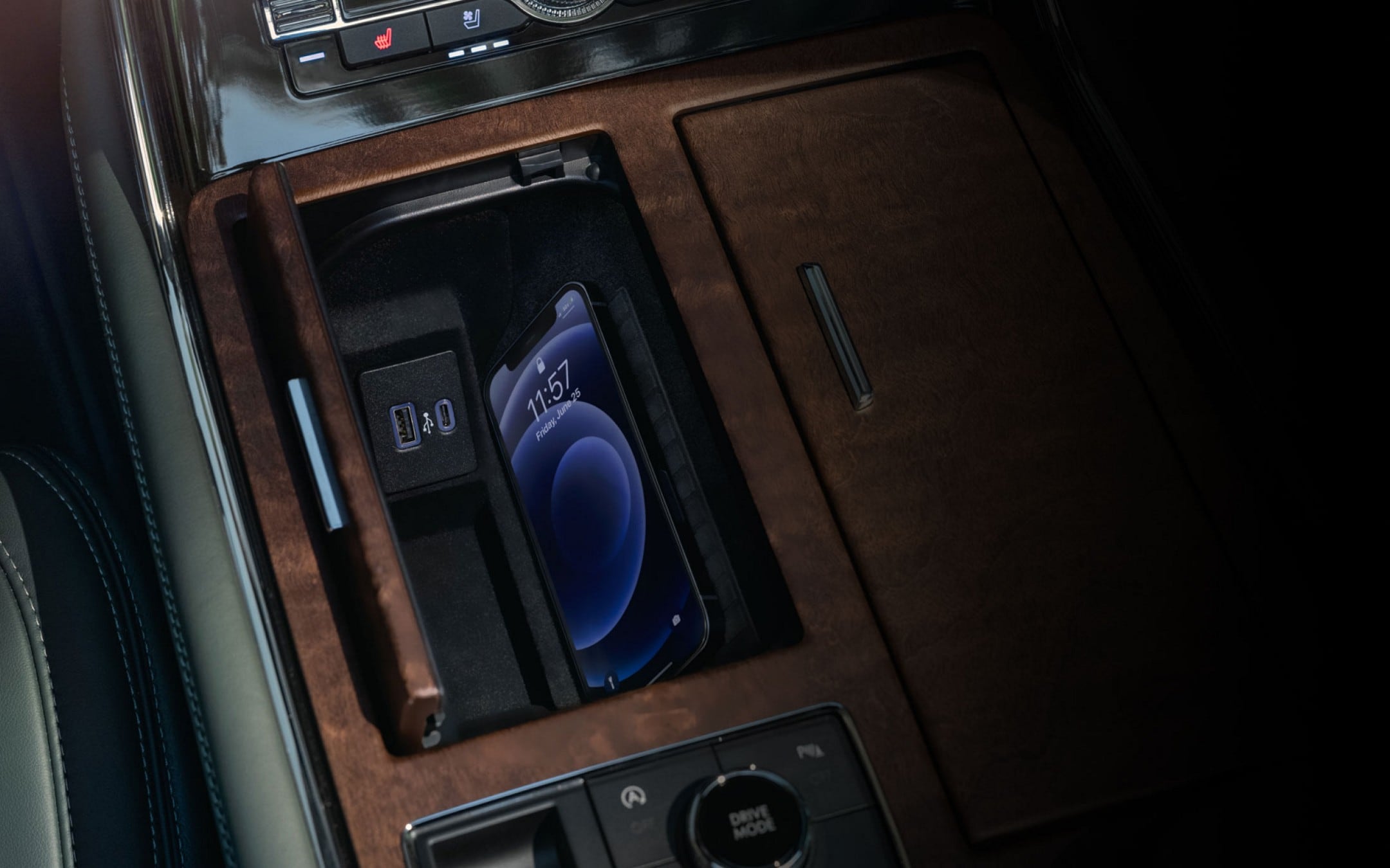 A smartphone is charging on the wireless charging pad that is tucked in a cubby integrated into the front center console