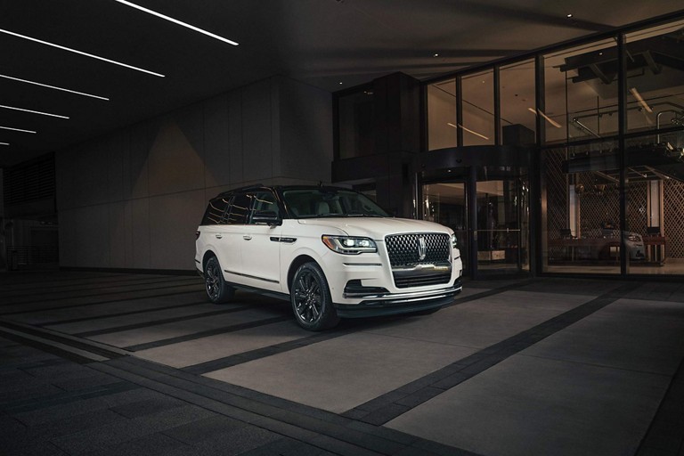 Una SUV Lincoln Black Label Navigator® 2024 con el paquete de edición especial está estacionada afuera del vestíbulo de un hotel de lujo.
