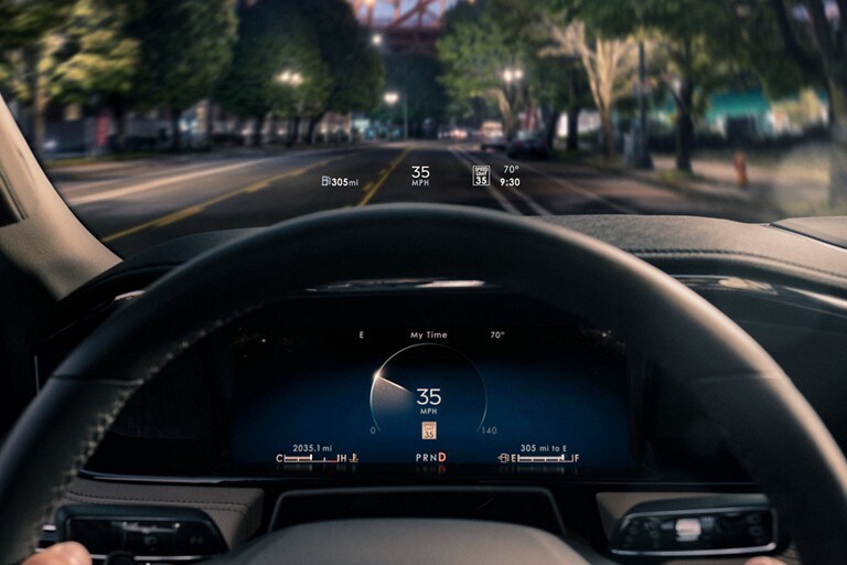 Head-up display information is being projected above the steering wheel at night.