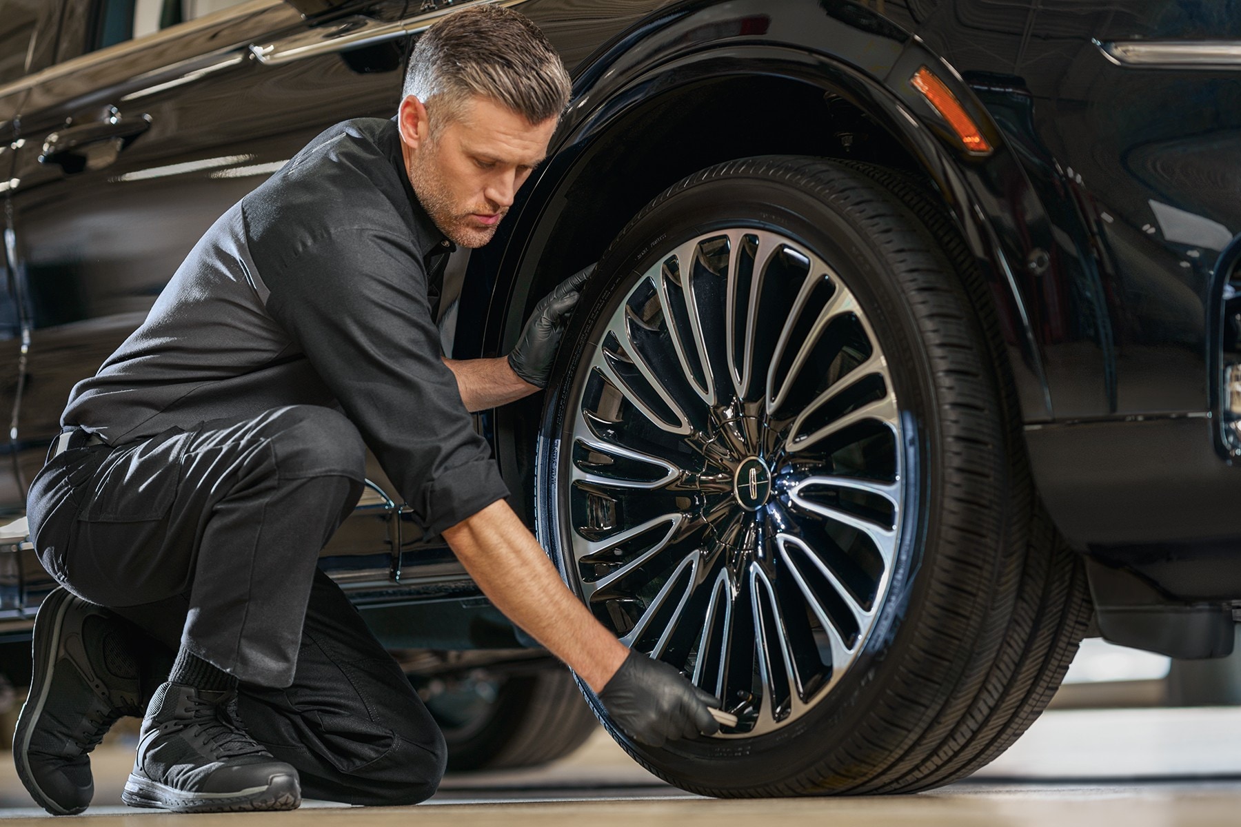 Man working on the wheel rim of a Lincoln vehicle.