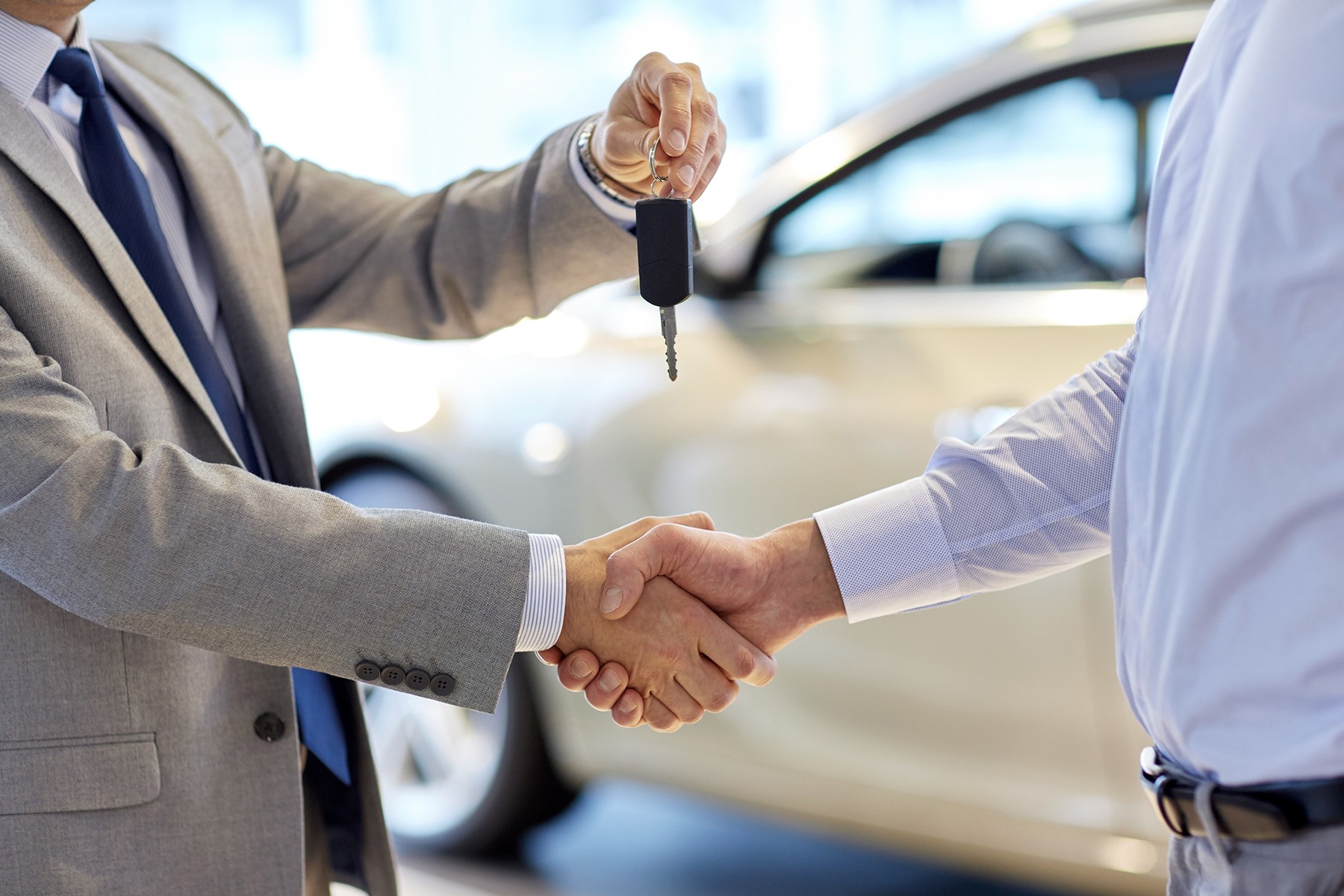 A man handing over they keys to a vehicle to another man.