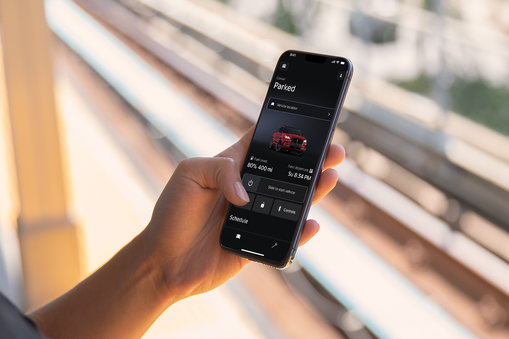 A woman is shown walking to a Lincoln vehicle while holding a mobile device displaying Vehicle Health Alerts.