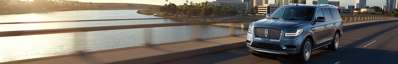 Luxurious blue Lincoln Navigator driving on a bridge over water