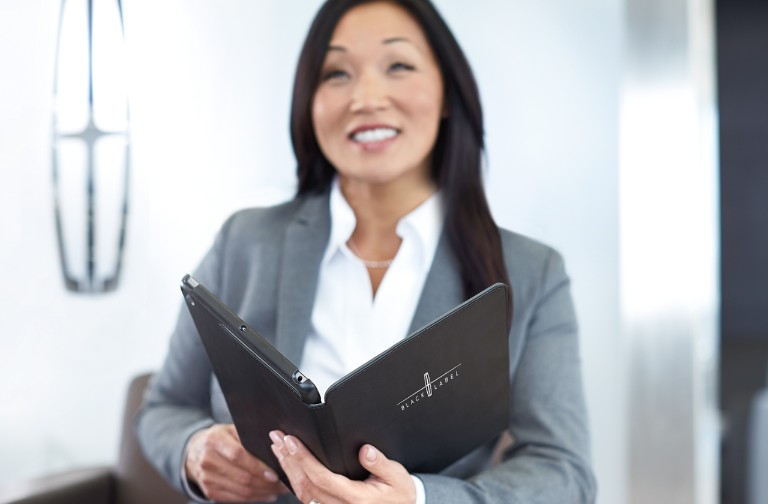 Woman in a grey suit in a Lincoln office holding a black tablet with custom Lincoln cover