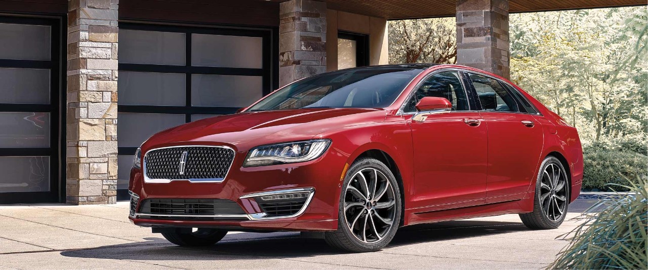 Luxurious red Lincoln M K Z sedan in front of a modern home´s garage