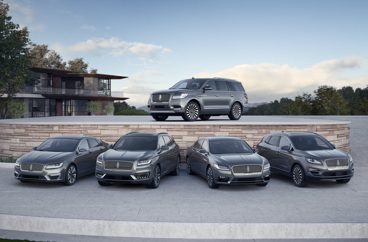 Full lineup of Lincoln luxury vehicles in silver with a modern home in the background