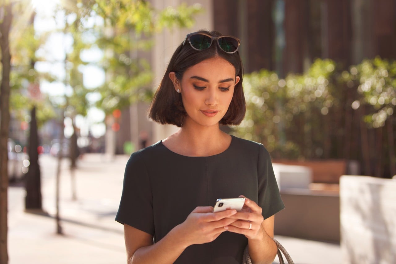 Woman holding phone outside building