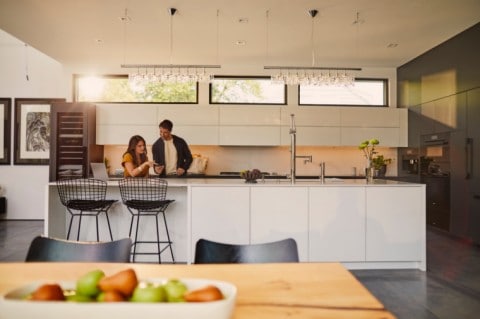 Man using phone next to large window with Lincoln vehicle seen on driveway below