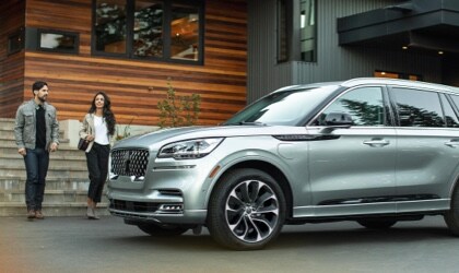 A man and a woman walking away from a modern home toward a 2023 Lincoln Aviator® Grand Touring